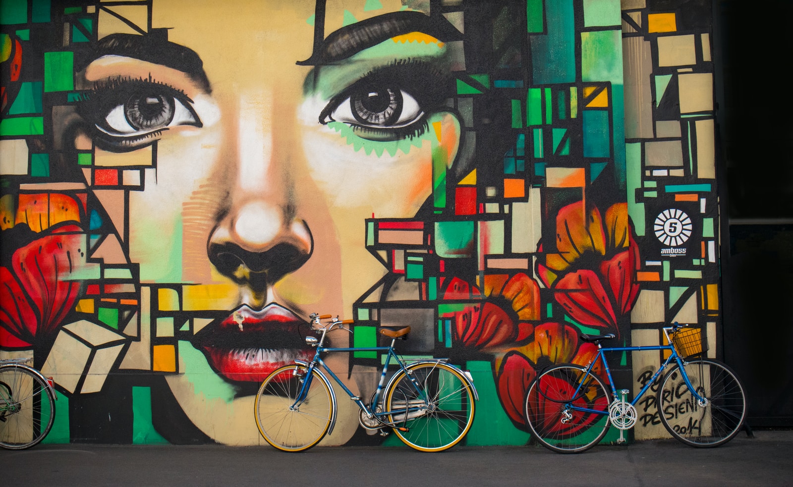 two blue cruiser bicycles on graffiti wall